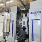 Technicien effectuant la maintenance d'une machine Mikron UCP 710 avec une broche démontée.